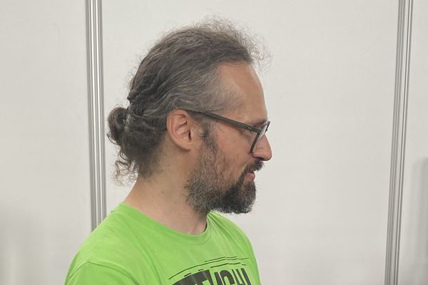 Michael Mattern im grünen TinyTechLab-Shirt im Profil, mit einem Gerät in der Hand