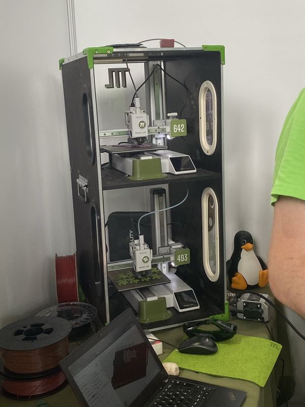 Zwei 3D-Drucker übereinander in einem schwarzen Transportregal, daneben Filamentrollen und ein aufgeklappter Laptop