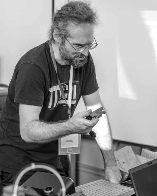 Michael Mattern an einem Messestand, über ein Bauteil gebeugt